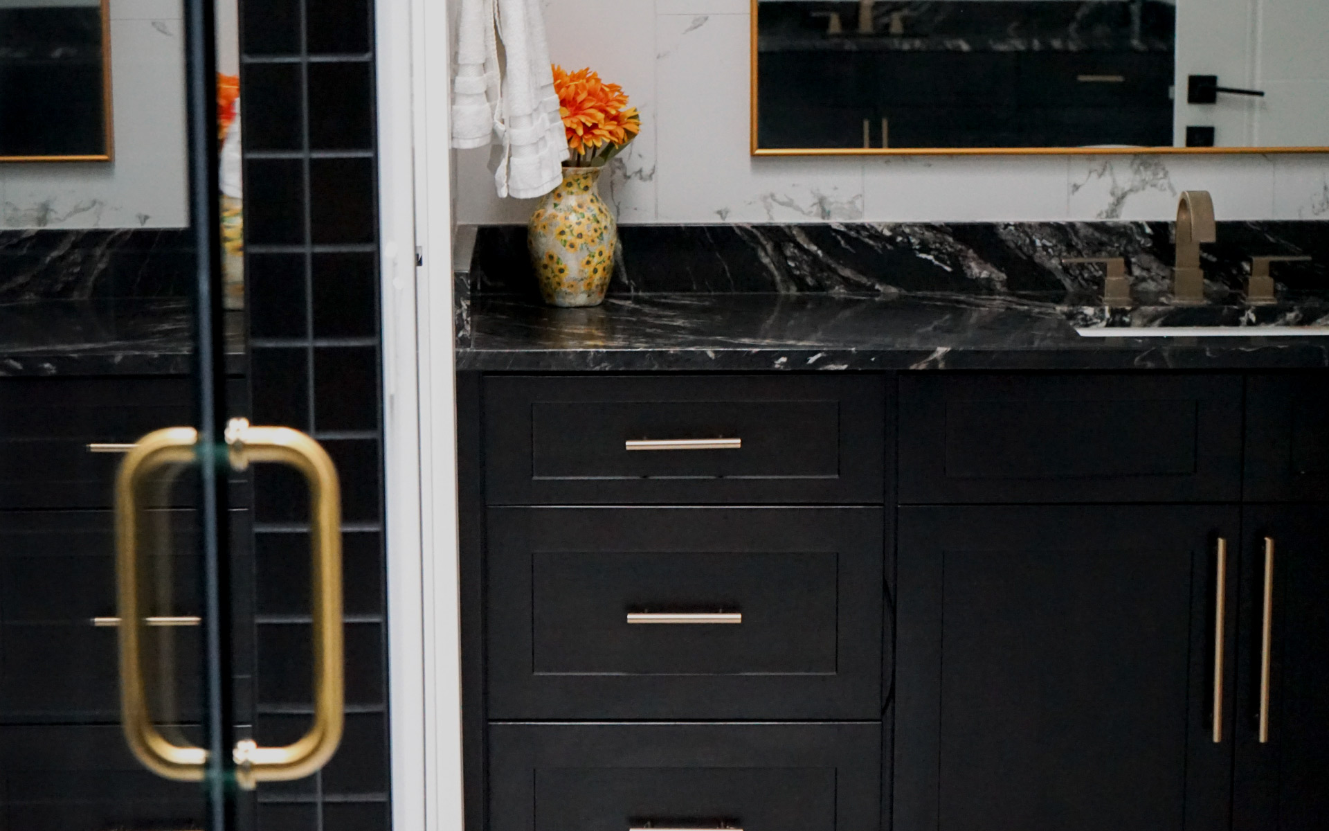 Modern black bathroom vanity with black marble countertop, gold hardware, and white tile wall in a Herndon, VA home remodel.