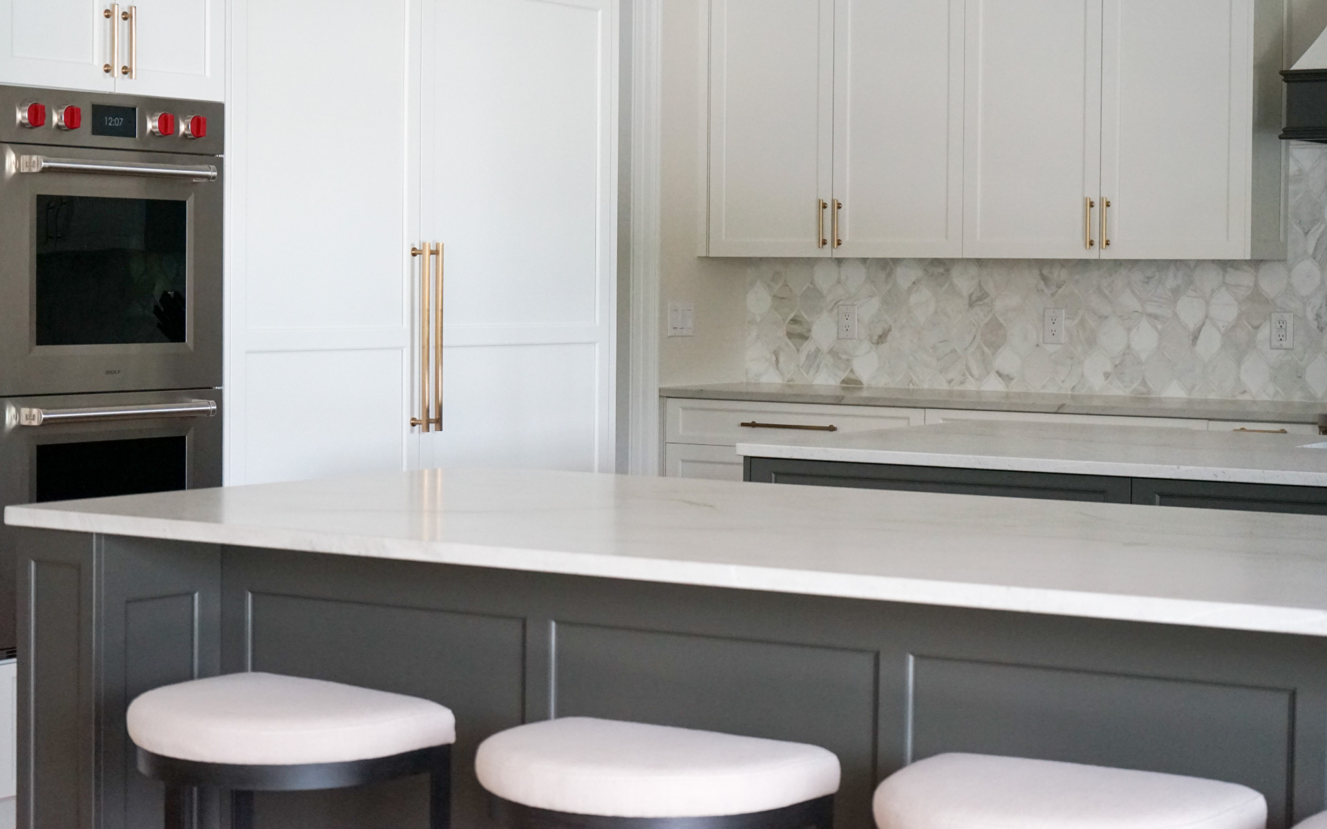 Modern kitchen remodel in Virginia featuring a dark grey island with white quartz countertop, white cabinets, gold hardware, and stainless steel double wall ovens.