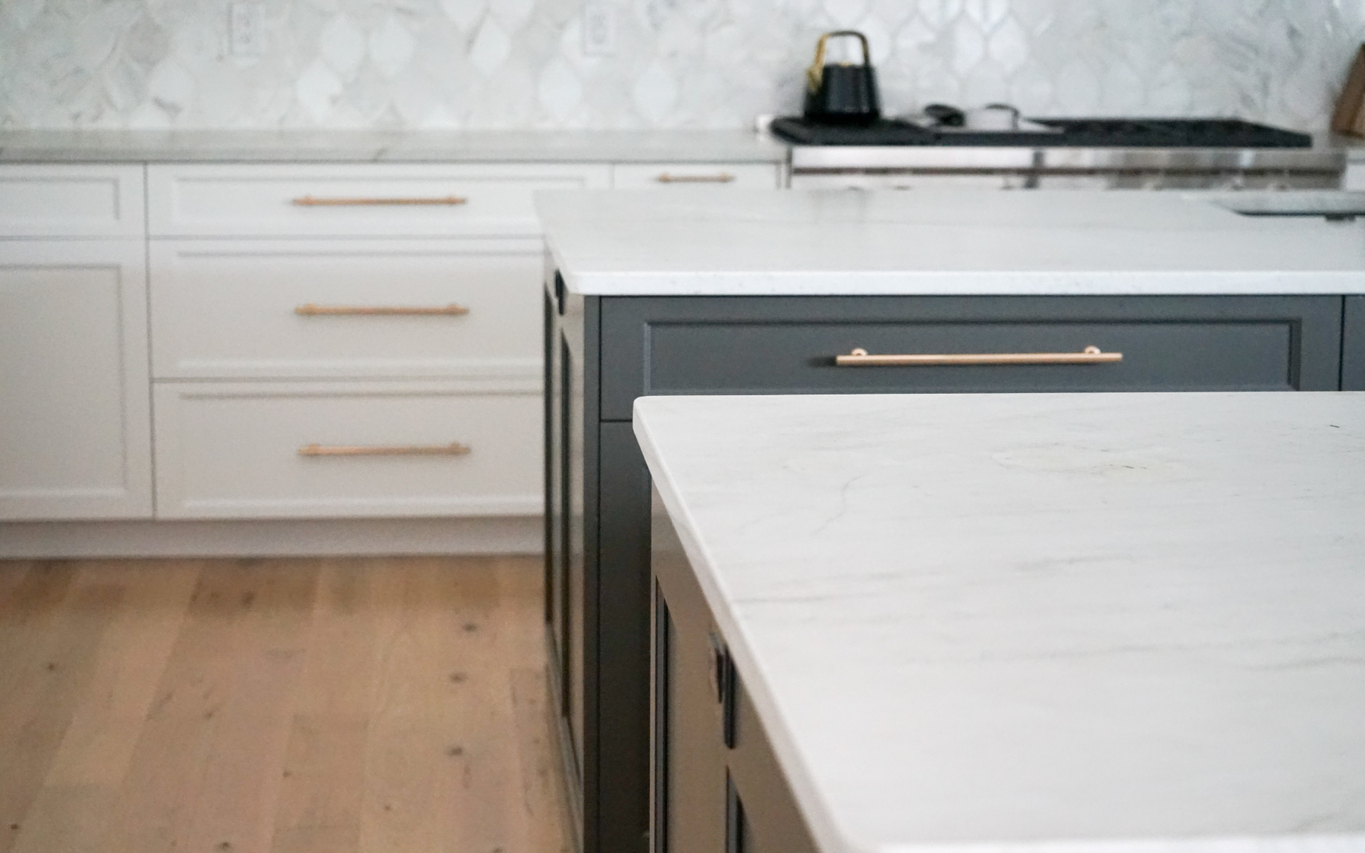 Modern kitchen remodel in Virginia featuring a dark grey island with white quartz countertop, white cabinets, gold hardware, and stainless steel double wall ovens.