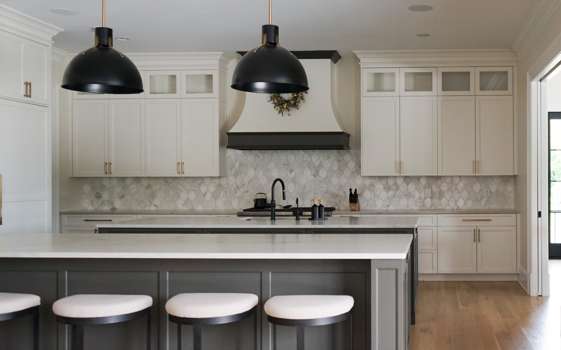 Modern kitchen remodel in Virginia featuring a dark grey island with white quartz countertop, white cabinets, gold hardware, and stainless steel double wall ovens.