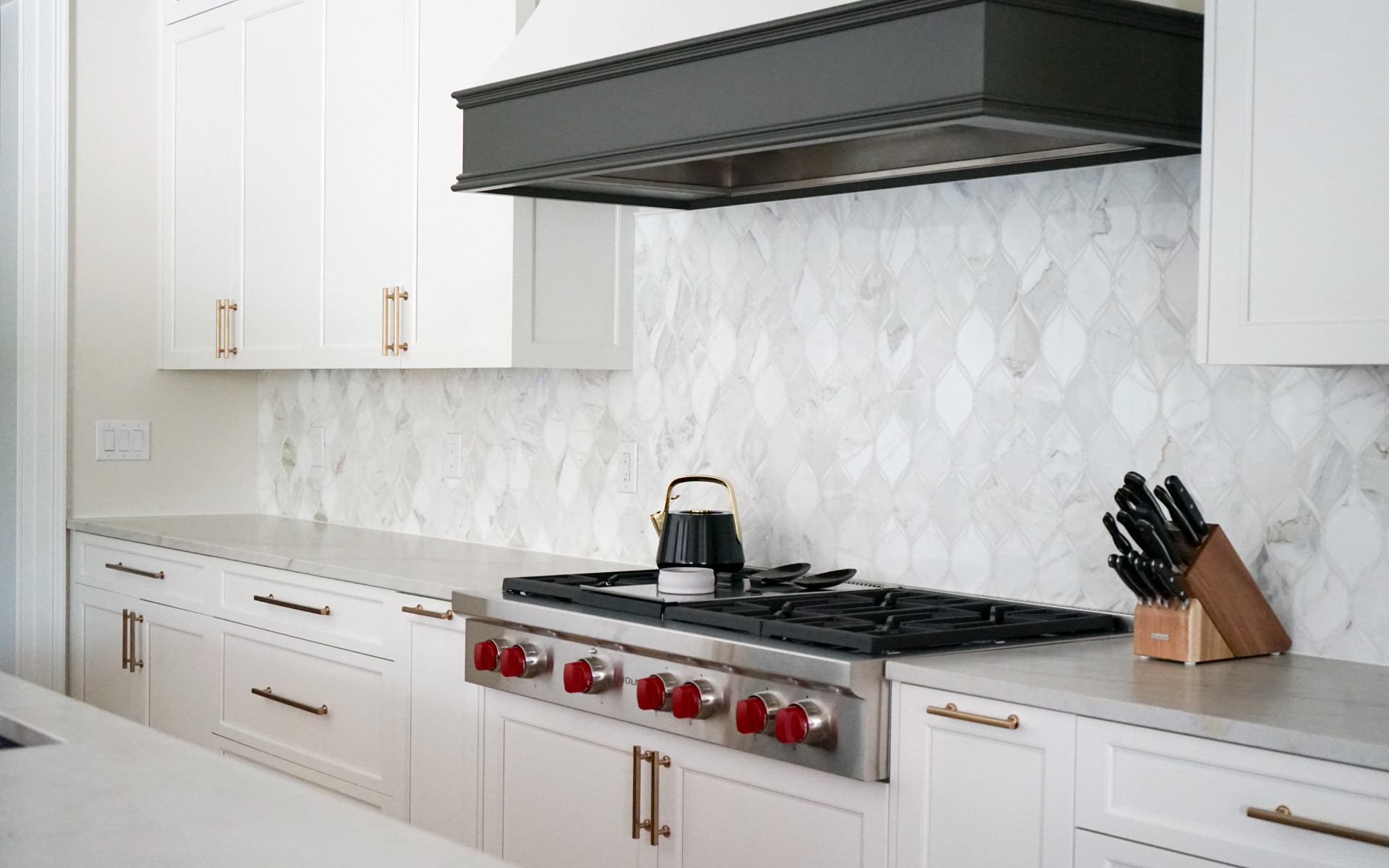 Modern kitchen remodel in Virginia featuring a dark grey island with white quartz countertop, white cabinets, gold hardware, and stainless steel double wall ovens.
