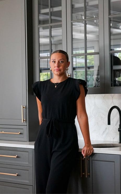 Designer at a home wet bar with grey cabinets.