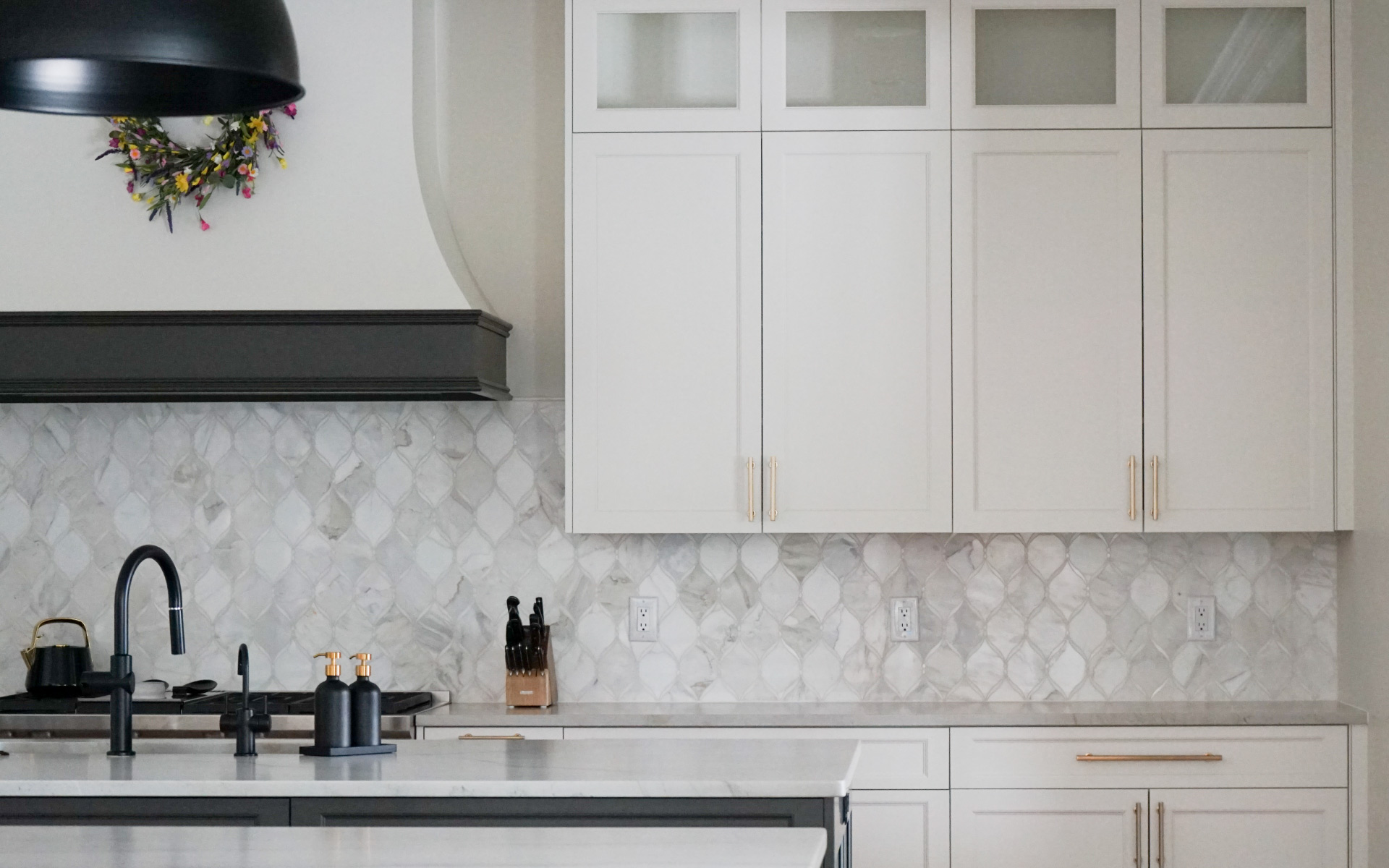 Modern kitchen remodel in Virginia featuring a dark grey island with white quartz countertop, white cabinets, gold hardware, and stainless steel double wall ovens.